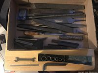 Box of assorted vintage hand tools including chisels, punches, wrench, sockets, and Allen key.