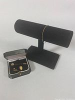 Photo shows black jewelry box with owl pendant, owl studs, and a pin with letter P, and a black display stand holding the bracelet.