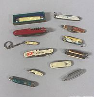 Overview of 12 assorted vintage pocket cutters laid out showing various styles, handle materials, and sizes