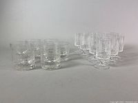 Side view of 19 Rosenthal crystal glasses, short tumblers left, stemmed glasses right, showing clear textured floral pattern.