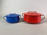 Front view of the blue and red enamel covered pots with lids and handles, showing their size difference and condition.