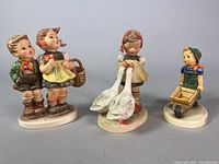 Front view of all three Goebel porcelain figurines showing boy and girl with basket, girl feeding ducks, and child pushing wheelbarrow.
