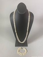 Full view of the necklace displayed on a black bust and bracelet laid flat below it showing the overall length and design.