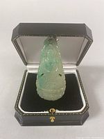 Front view of the carved jade Buddha pendant displayed upright in jewelry box.