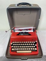 Red Royal Quiet DeLuxe portable typewriter inside open gray fiberglass case