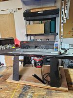 Front angled view of Craftsman router mounted on router table with bits and accessories around it