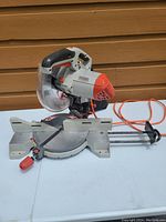 Photo of 10-inch Ridgid miter saw on white table showing the full tool with blade guard, base, and power cord.
