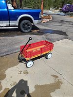 Photo of a red Road Master Woody Wagon on concrete with a blue pickup truck in the background.