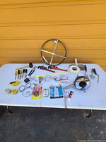 Photo of various assorted hand and plumbing tools on a white table against yellow wall.