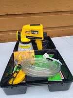 Photo showing Wagner Power Painter 6.0 wide spray paint sprayer unit in yellow and black, along with accessories and literature in black tray.