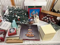 Overview photo showing Christmas light string, boxed silver-plated item, ceramic bells, decorative figurine, and boxed holiday decor