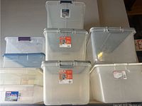 Overview of six clear and semi-transparent plastic storage containers with lids, stacked and displayed on a flat surface.
