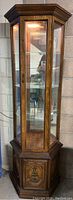 Full view of the curio cabinet showing glass panels, wooden frame, and the door with decorative handle.