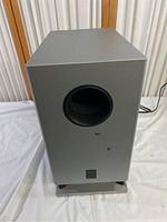 Front and side view of Onkyo SKW-8230 powered subwoofer showing port hole and grey cabinet.