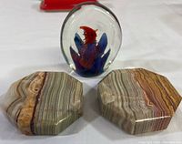 Front view showing two onyx paperweights with natural stripes and one glass paperweight with colorful internal design.