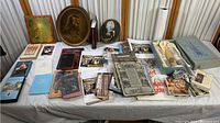 Wide-angle photo showing the full collection of religious items arranged on a table, including framed prints, books, pamphlets, and boxes.