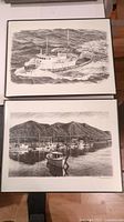 Two framed black and white prints stacked, showing a tugboat and a marina scene with boats.