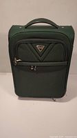 Front view of green Antler carry-on luggage with triangular logo, front zippered pocket and top handle.