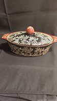 Front view of blue harbor collection covered casserole baking dish showing black and white floral patterns with reddish-brown trim and knob