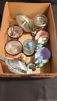 Box containing a variety of decorative items including glassware, figurines, and snow globe.
