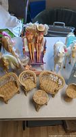 Photo showing three vintage Barbie dolls seated on rattan furniture with four horses in the background.