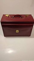 Front view of vintage burgundy leather pilot briefcase showing front pocket with lock and brass locks on top with handle