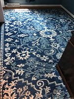 Full view of the Surya Harput blue floral area rug in a room corner, showing pattern and condition.