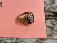 Front-left perspective showing raised school crest on black enamel face