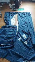 Six navy blue blackout curtain panels with visible white lining, laid out on the floor including rod, hooks, and ropes.