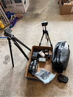 Overview showing two tripods, camcorder batteries, charger, and carrying case on the floor.
