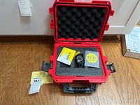 Red hard plastic protective case opened showing Invicta watch and paperwork inside foam padding