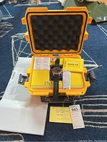 Yellow hard protective case open with foam interior, containing Invicta Aviator watch, warranty card, and paperwork