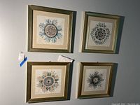 Four square frames hanging on wall, each containing a unique jellyfish art print with blue, beige, and brown tones. Gold-toned frames with glass cover visible.