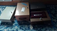 Four metal lock boxes positioned on a blue patterned rug with one containing a maroon bank bag labeled Meridian Bank. Variations in size and color visible.