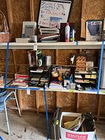 Wide view of white shelving with file folders, trays, briefcase, paper pads, markers, stapler, envelopes, and cleaning spray bottles in garage space