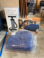 Photo showing boxed Intex Queen air mattress, folded second mattress in plastic, and boxed heavy duty push pull pump.