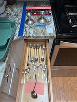 Overview photo shows eight sterling silver shakers in box, two sterling candlesticks, sterling ladle and assorted silverplate spoons/forks in drawer