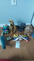 Photo showing all six stuffed animals: Y2K Bug, two dragons, bat, bear, dinosaur, displayed on floor.