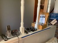 Multiple Panasonic cordless phones and accessories arranged on a ledge, showing three cordless phone units with handsets and charging bases.