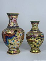 Two Chinese cloisonne vases side by side against a white background showing detailed cloisonne enamel work with gold backgrounds and dragon motifs.