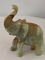 Side front view of the translucent marble onyx carved elephant showing raised trunk and detailed ears with natural veining.