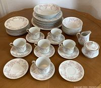 Full set of Premiere April Rose china arranged on a table showing all listed items including plates, cups, saucers, bowls, large bowl, platter, and sugar bowl with lid.