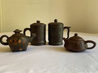 Overview of four clay vessels: turtle teapot, squat teapot, two lidded mugs