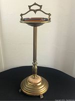 Full view of the vintage ashtray stand showing brass construction, circular ashtray and handle.