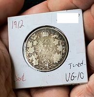 Reverse side of 1912 Canadian 50 cent coin showing denomination, date, maple leaf design and toning in 2x2 flip holder.