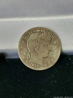 Front side of 1912 USA Barber Quarter coin showing Lady Liberty and date.