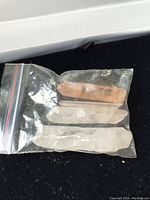 Four quartz crystal specimens in a small clear resealable plastic bag against a black surface.