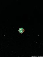 Loose green fire opal gemstone with iridescent color flashes on black background, showing green and orange hues.