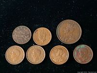 Seven old Canadian one cent coins with varying designs and wear. Coins include 1928, 1910, 1932, and others, mostly featuring King George V.