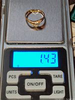 Yellow gold diamond ring placed on a digital scale showing weight 1.43 grams.